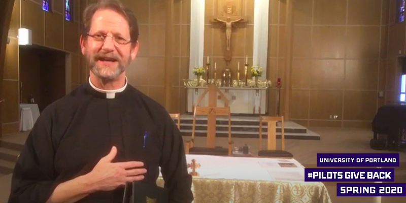 Fr. John Kerns in front of altar with logo that reads University of Portland Pilots Give Back Spring 2020