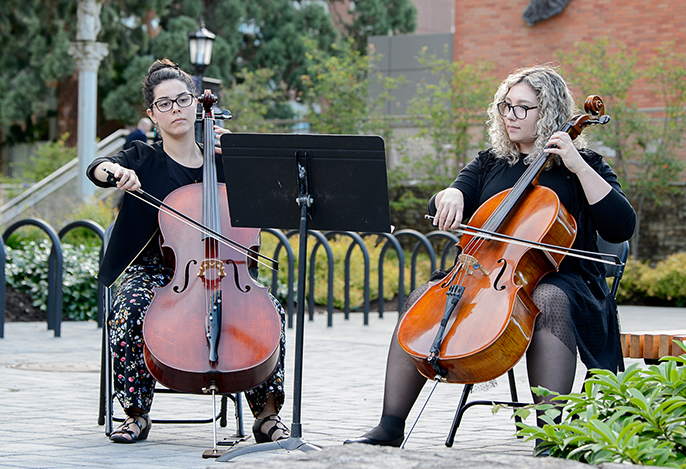 Two women playing cello outside