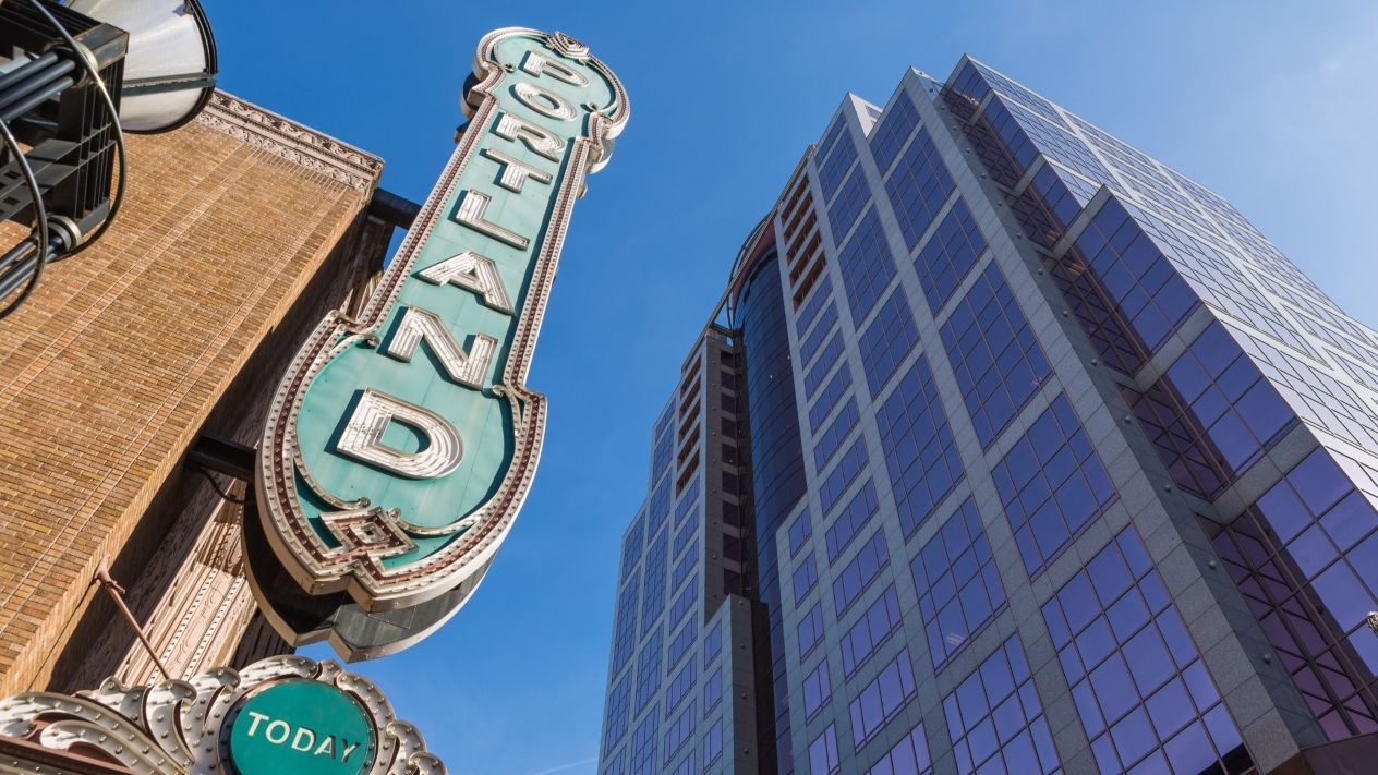 A low angle image looking upwards at an ornate antique theater sign that says "Portland".
