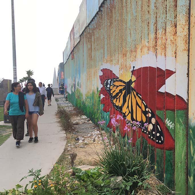 Border wall with the artwork of a monarch butterfly upon it.