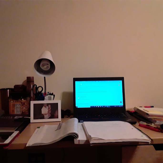 A desk with a computer, textbooks at notebooks open.