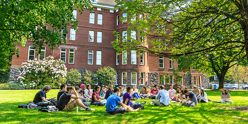 students and professor sitting outside of building