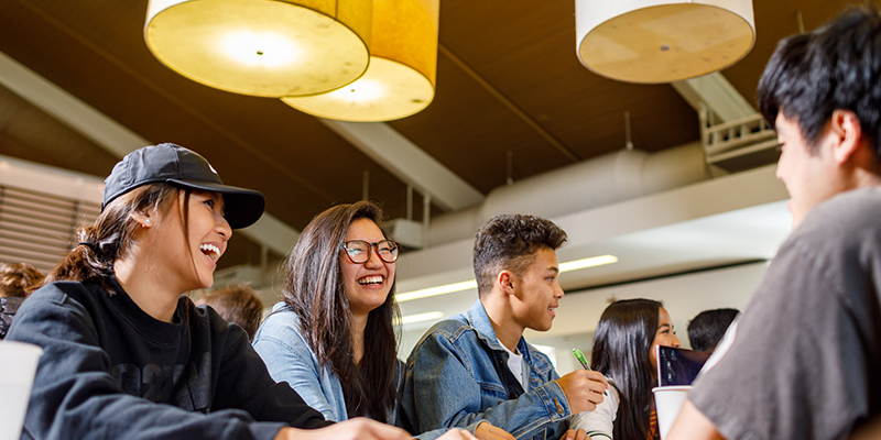 students sitting at table laughing and talking