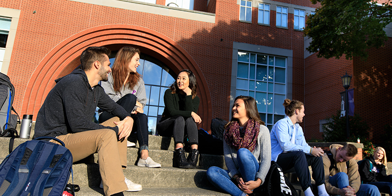 students on University of Portland campus sitting on brick steps
