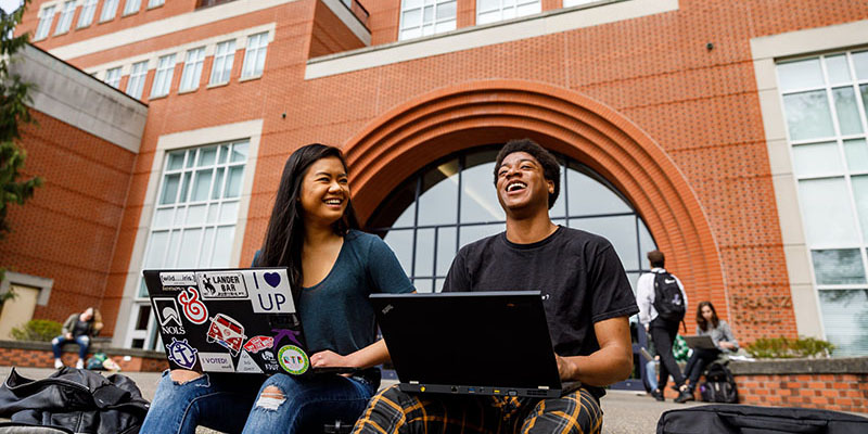 students sitting on steps with laptops