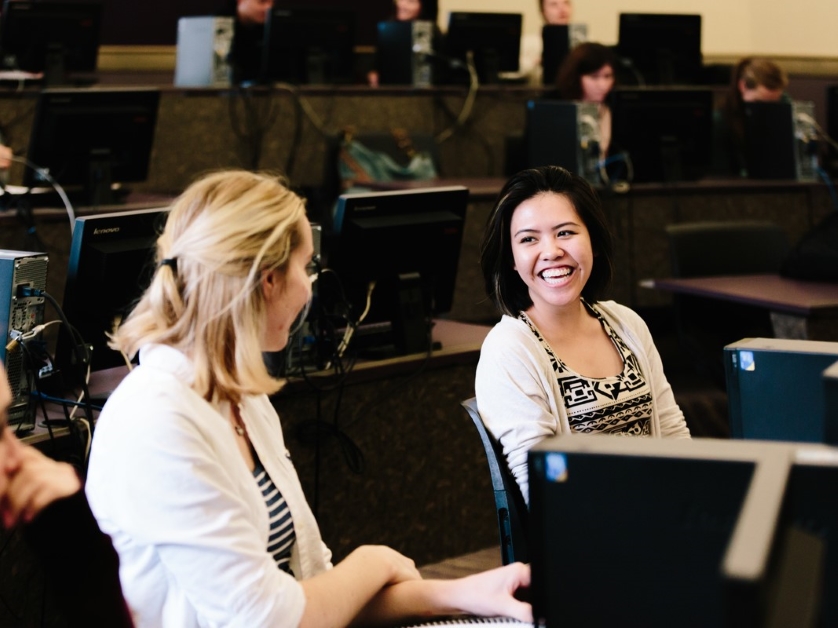 Two students smile and laugh in a classroom