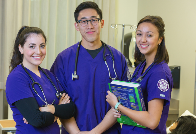 UP student male and female student nurses in purple scrubs in the lab.