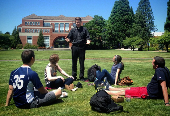 Priest teaching class outside.