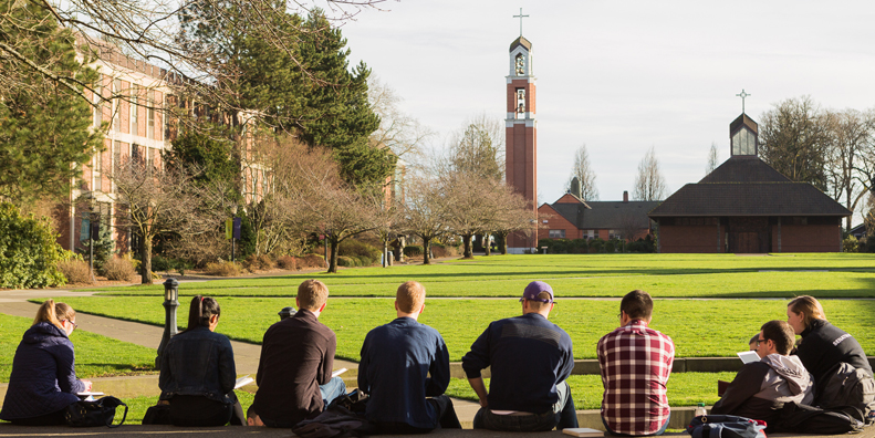 Students sitting on the steps outside Franz Hall, facing the bell tower.