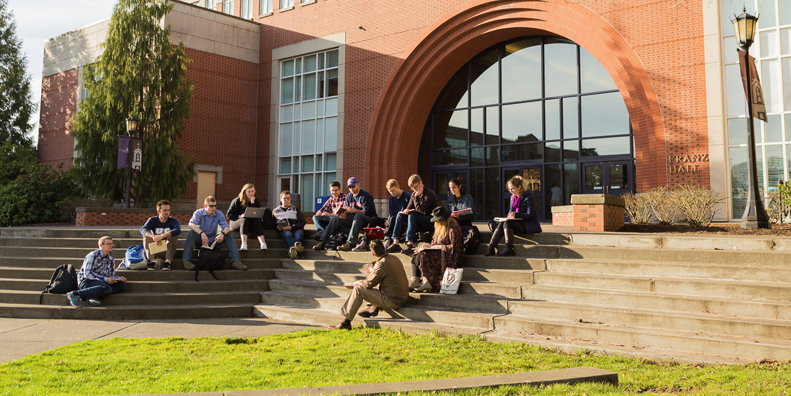 A class having class outside, sitting on the steps of Franz Hall.