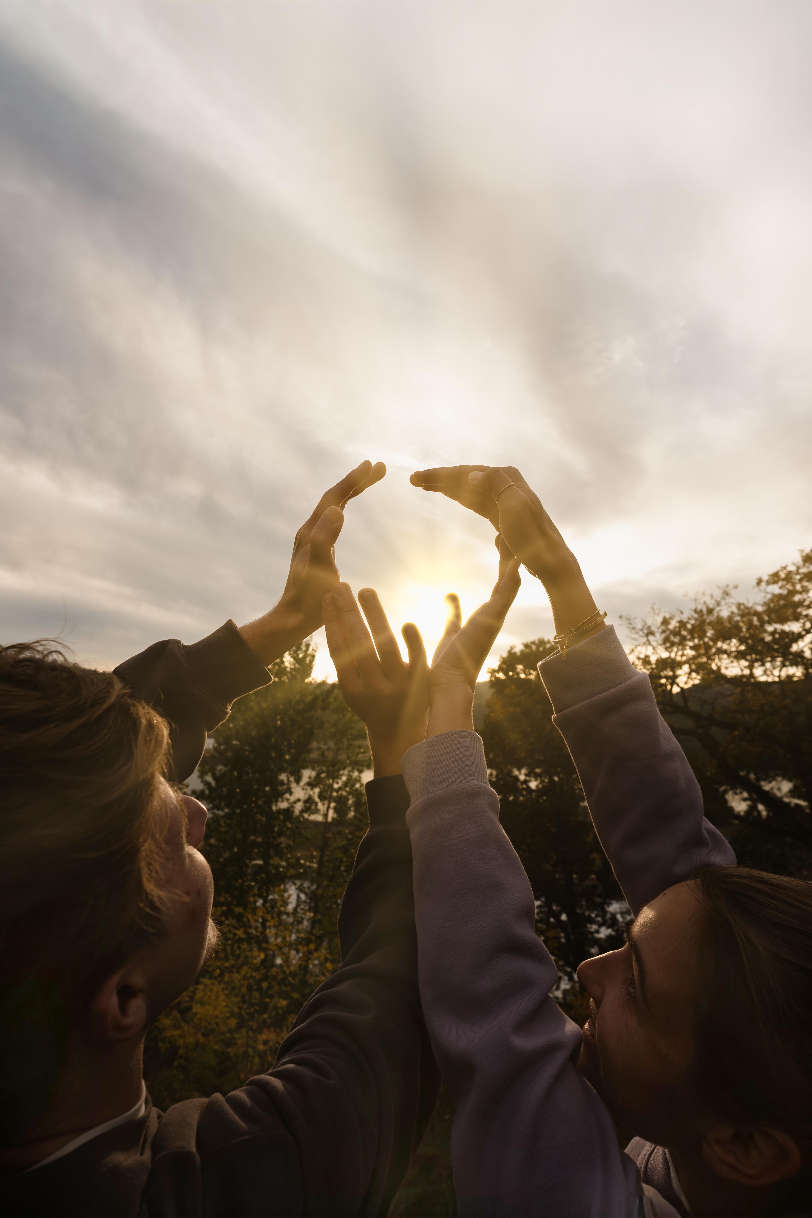 University of Portland students frame the sun with their hands as it breaks through the clouds and shines