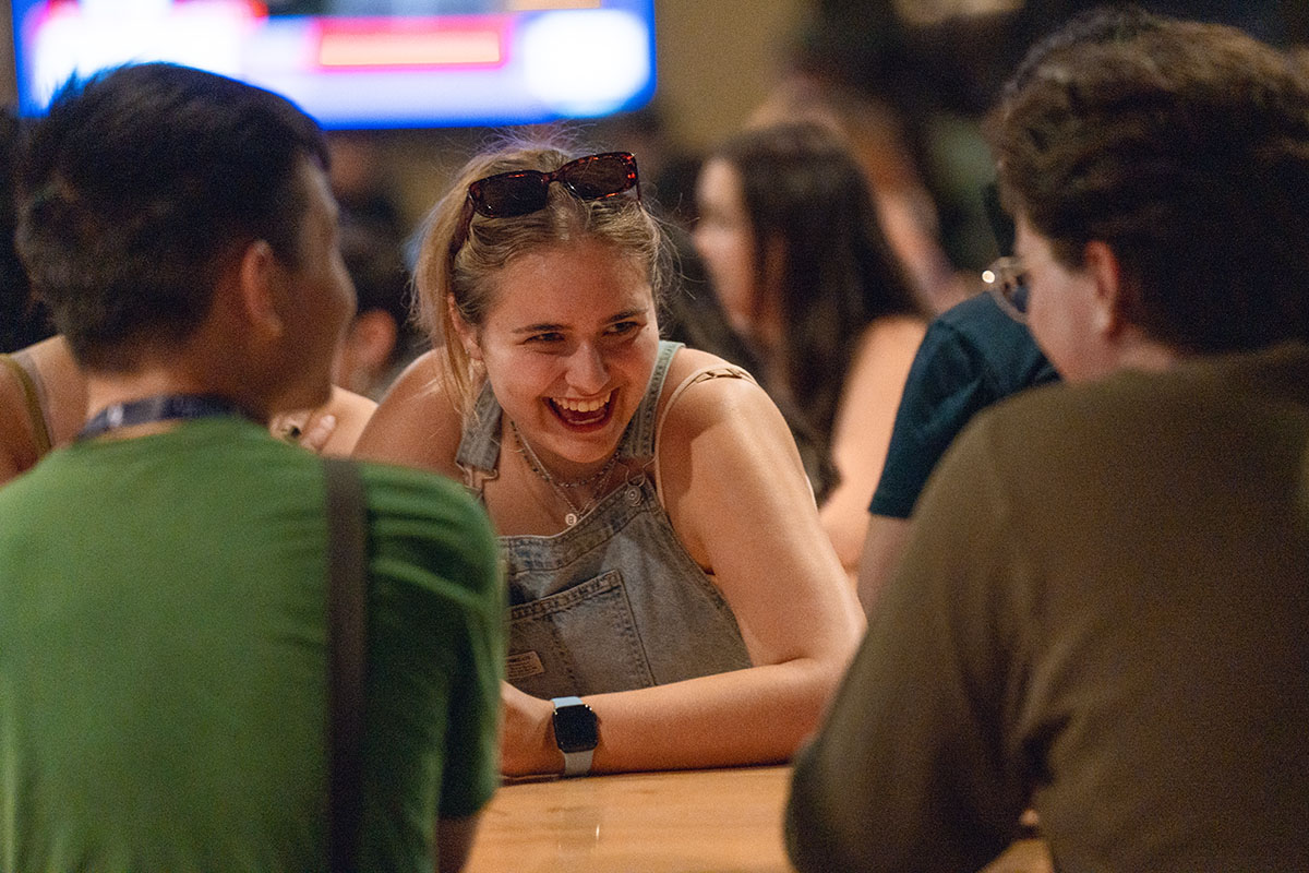 students sitting at table laugh during karaoke