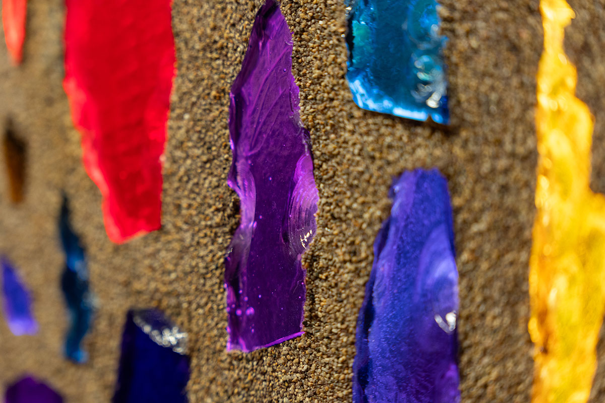 Close up photo of light shining through bits of colored glass in a mosaic