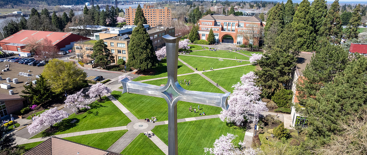 drone shot of the bell tower cross with the cherry blossom lined quad and franz hall in the background