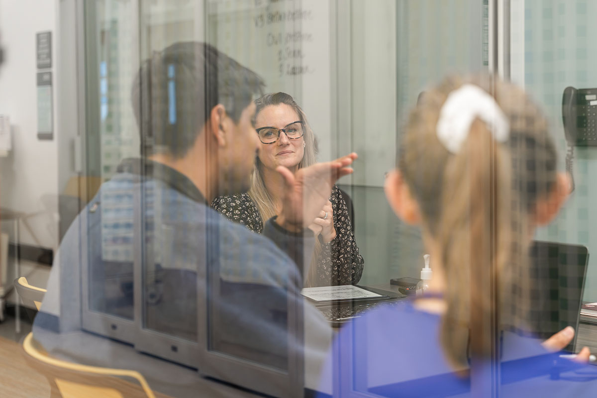 students and professor seen through glass in a small discussion group