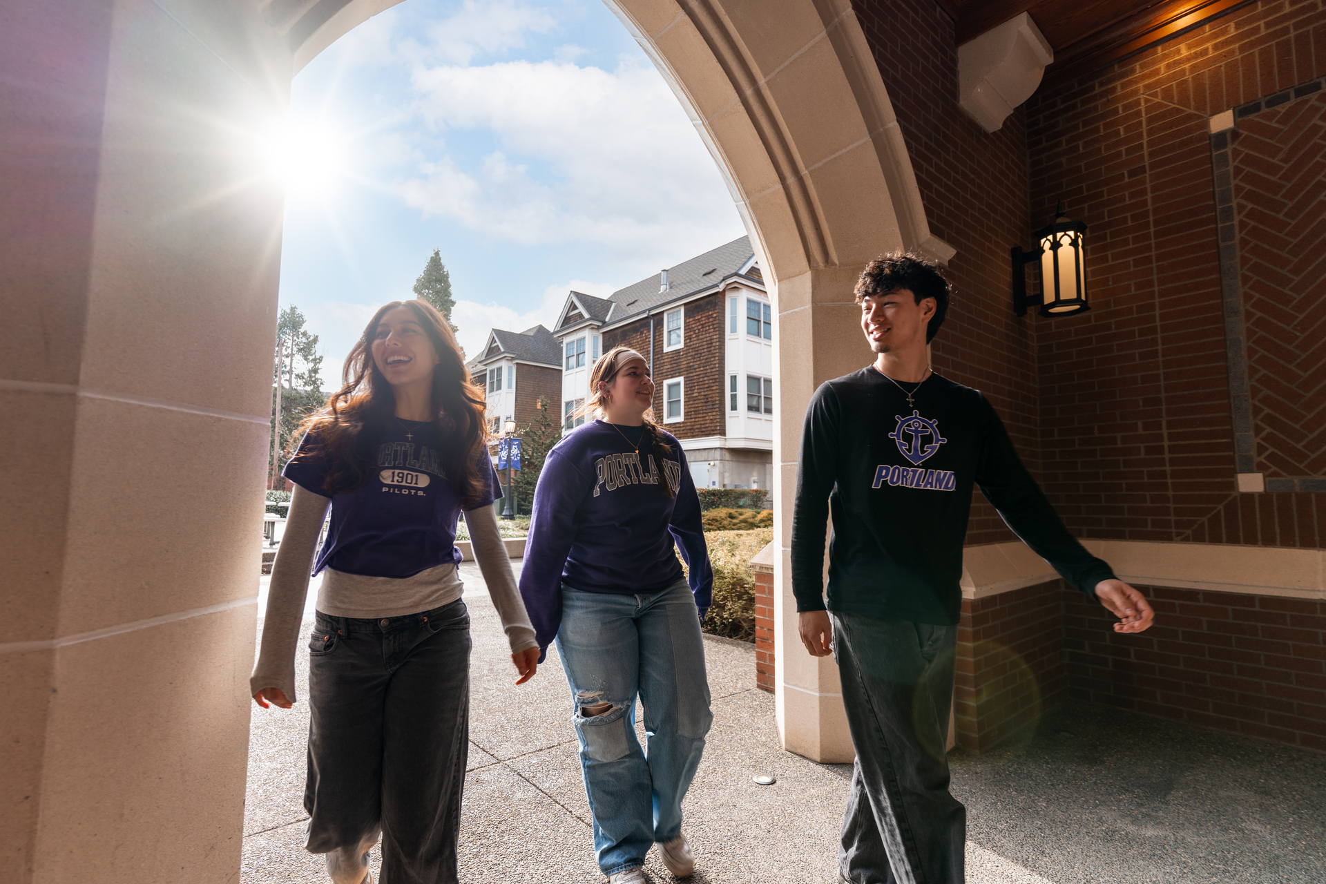 Three UP Pilots walk through the sunlit portico of Lund Family Hall.