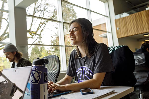 students smiling as they study at a table together in clark library on the University of Portland campus