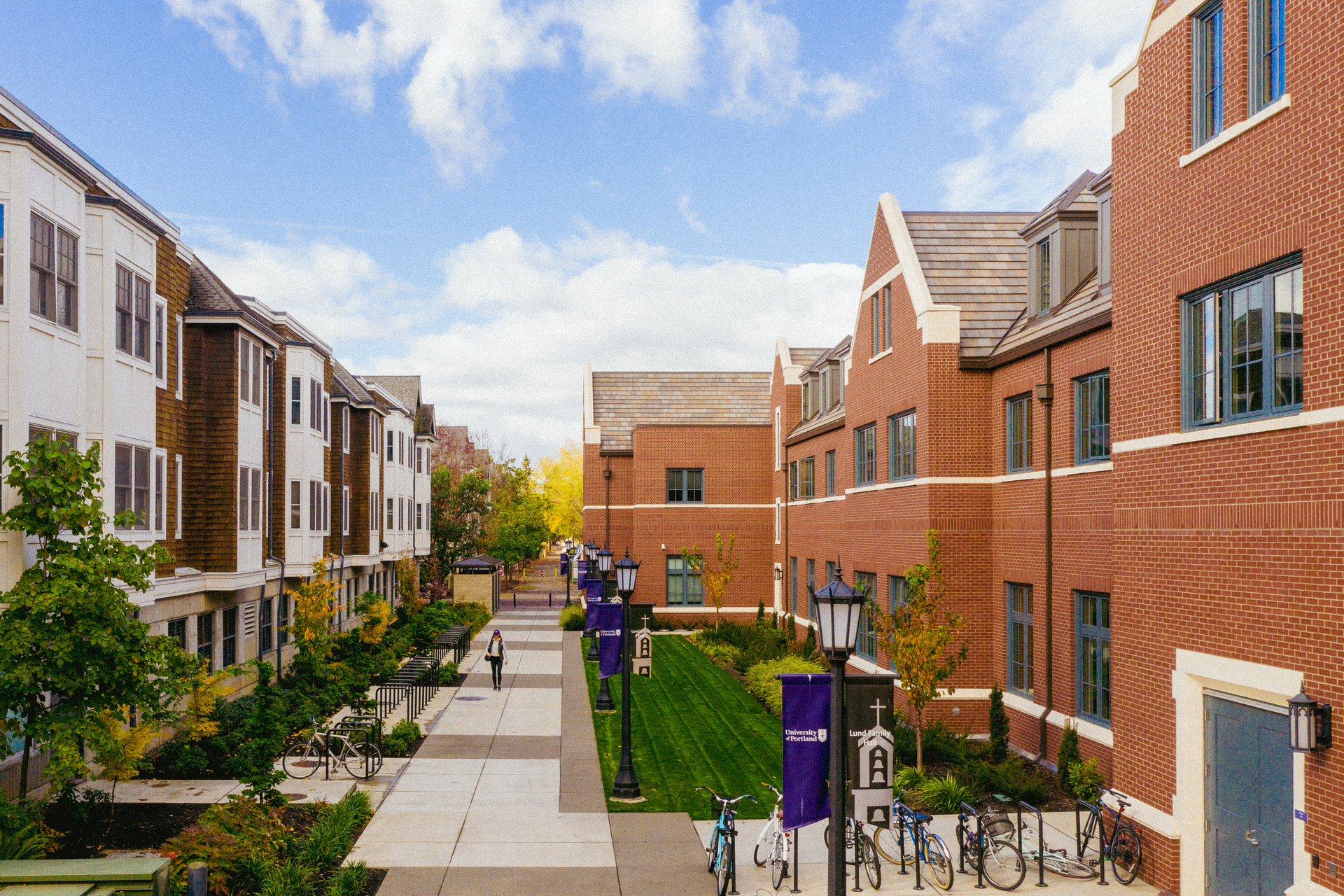 An elevated view of a student walking on the sidewalk between Haggerty and Tyson Halls on University of Portland's campus.