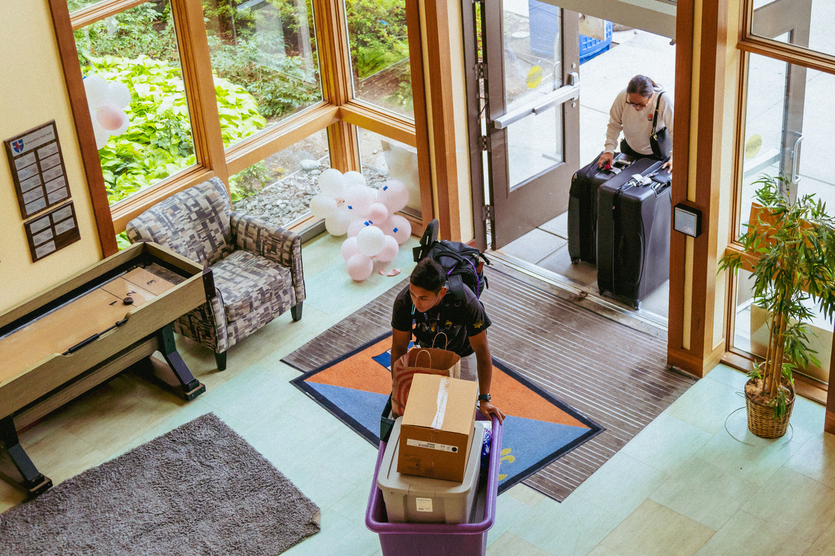 An above view of a UP student and parent bringing boxes and suitcases into the lobby of Fields Hall on move-in day.