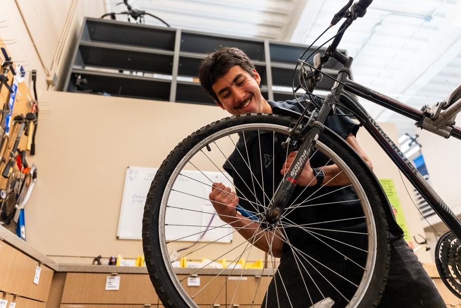 A student repairs a bicycle in the shop at the Outdoor Pursuits gear facility.