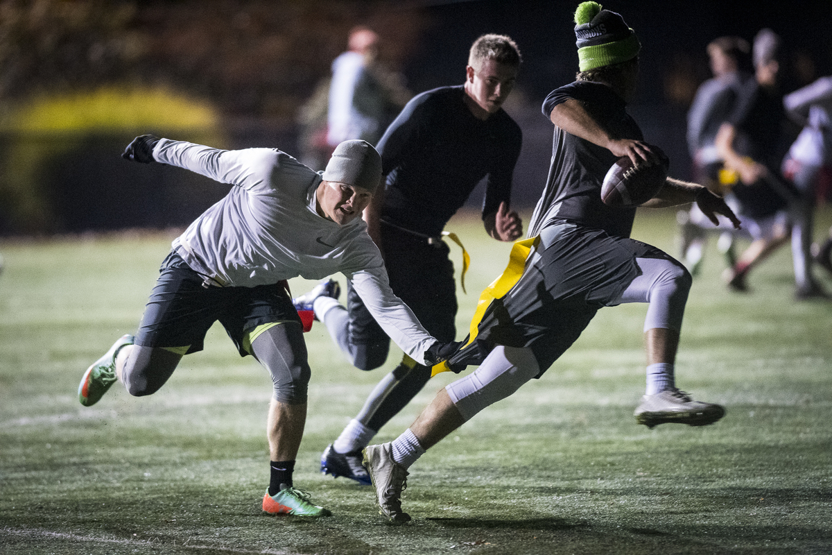 Students running on the field while playing a night game of intramural flag football
