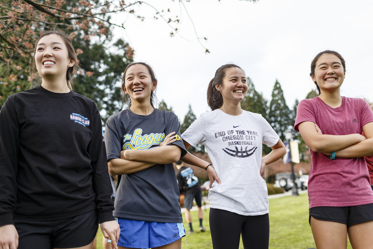 Four students standing outside and laughing during an intramural sports game at UP