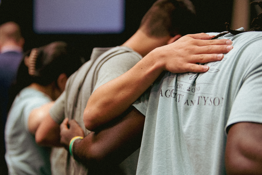 A close-up of three students standing with their arms around each other's shoulders during an orientation event.