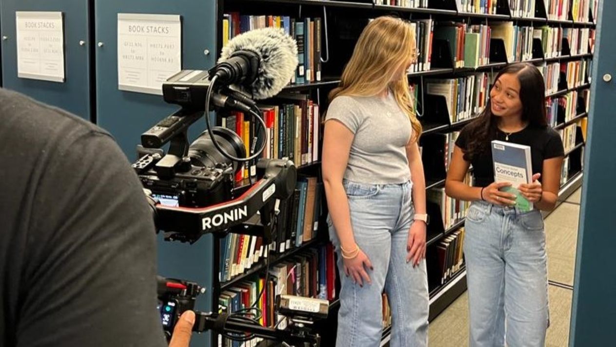 Students talking in front of a camera in the school library
