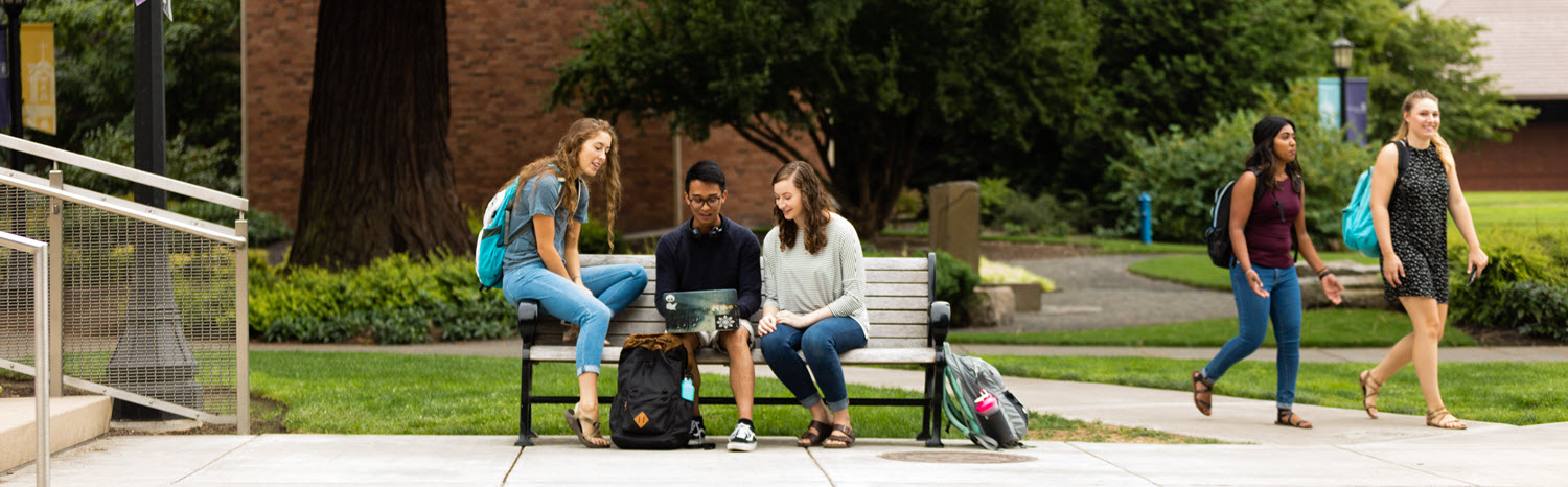 students sitting together on a bench outside