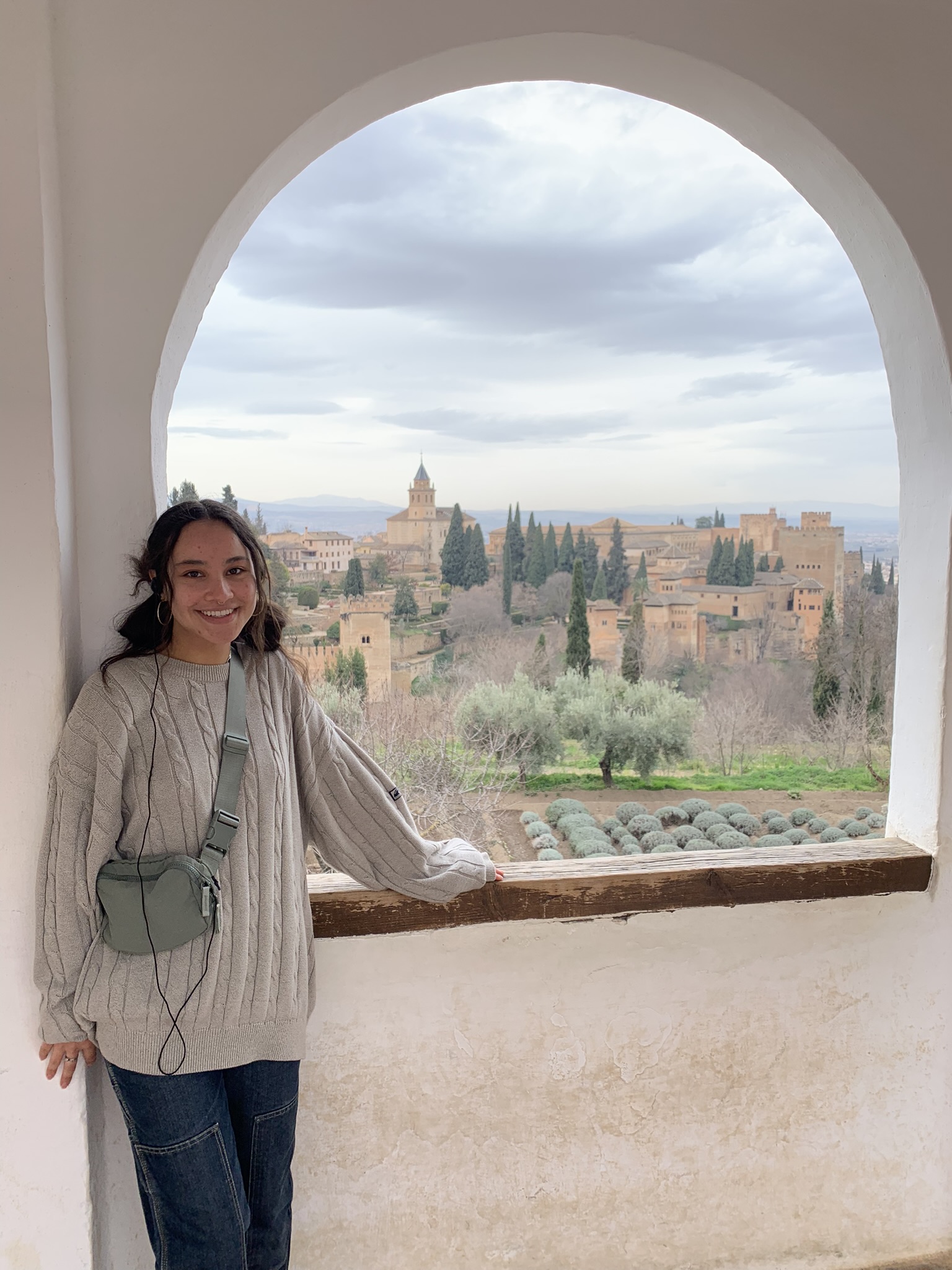 A study abroad student stands in a window overlooking a cityscape