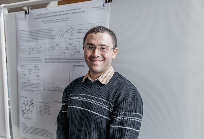 Student standing next to research poster