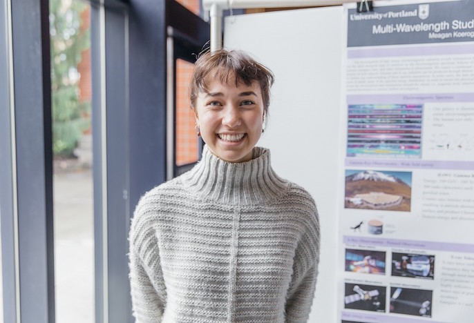 Student standing next to research poster