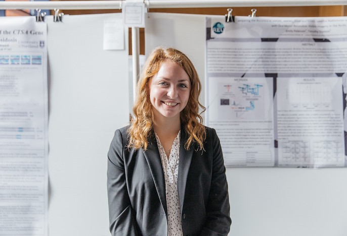 Student standing next to research poster